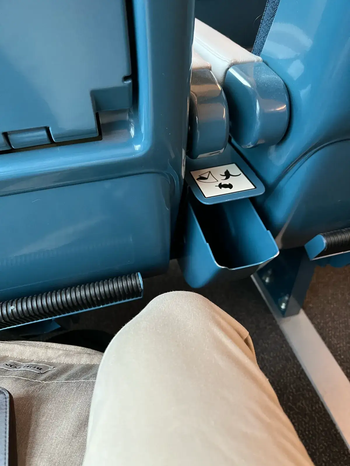 A small moulded waste bin built into the blue seat back of an SNCF train, marked with a litter pictogram